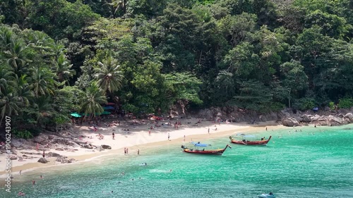 A pristine tropical beach, boats resting, clear turquoise water, and lush greenery offers a slice of paradise.