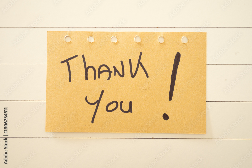 Obraz premium A thank you written on a sticky note. On a white wooden background.
