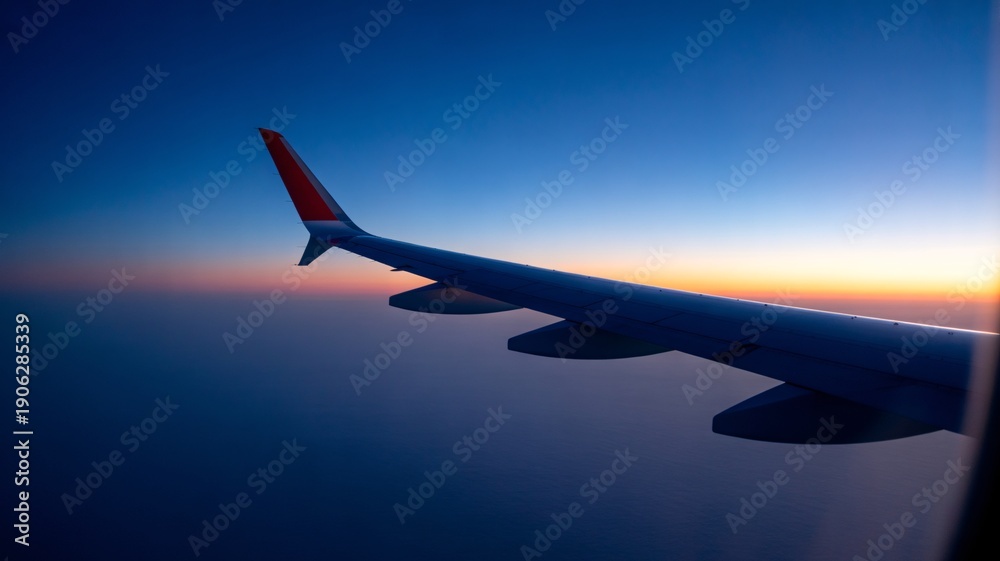 Obraz premium Airplane wing soaring through vibrant sunset sky during flight