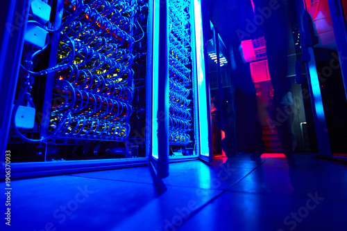 Canvas Print Low angle view of glowing blue server aisles in futuristic high density data ce