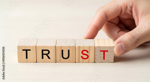 A hand building trust with wooden blocks on a white surface with a simple background