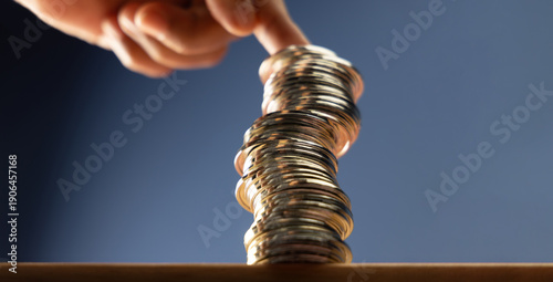 Quadro su tela Hands supporting unstable coin stack symbolizing financial risk, market uncertai