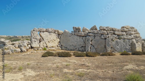 Ancient megalithic limestone wall at Ġgantija Temples in Gozo, Malta, prehistoric UNESCO site under clear blue sky.