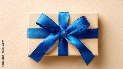A beautifully wrapped gift box with a blue ribbon on a beige background