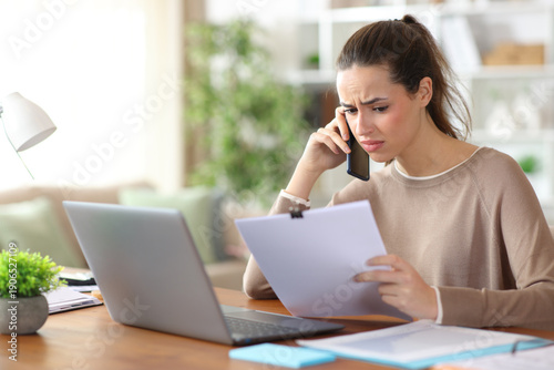 Confused tele worker talking on phone about paper report
