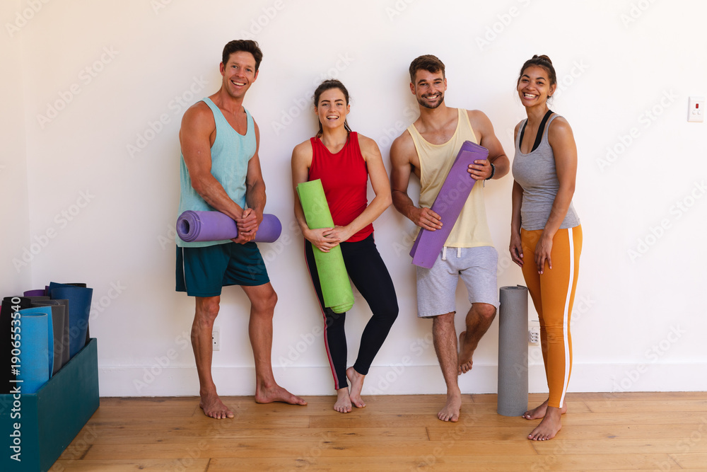 Obraz premium Portrait of smiling multiracial men and women with yoga mats against wall in yoga studio