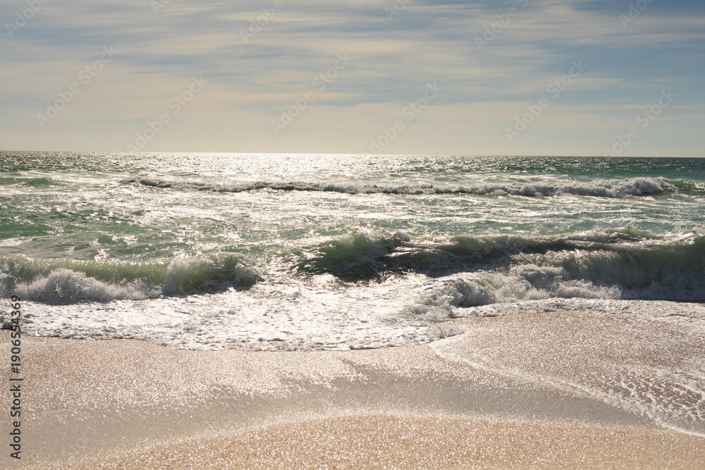 Obraz premium Scenic view of waves crashing on shore at beach against sky during sunny day