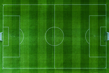 High-angle aerial top view of a pristine green soccer field. Professional football pitch with white markings, goal posts, and textured grass stripes. Perfect for sports and recreation designs.