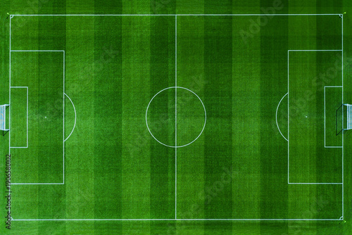 High-angle aerial top view of a pristine green soccer field. Professional football pitch with white markings, goal posts, and textured grass stripes. Perfect for sports and recreation designs.