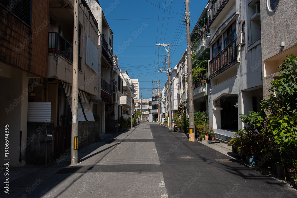 Obraz premium 2階、3階建ての建物が両側に並ぶ路地裏の半分が新しく舗装し直された直線の道