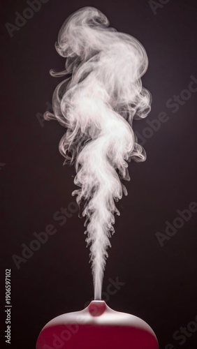Essential oil diffuser releasing aromatic steam on dark background  
