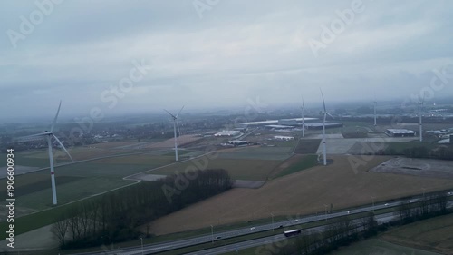 Aerial view of windmills standing tall in a field with a highway cutting through, creating a stark contrast of industry, Tournai, Belgium.