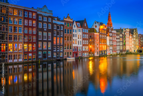 Houses over canal with mirror reflections in water at blue night, Amsterdam, Netherlands