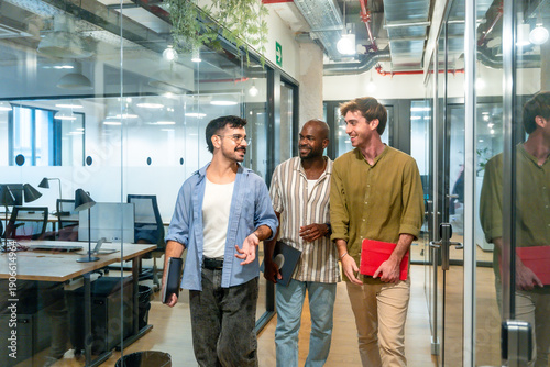 Photography Diverse male colleagues walking and talking during office break