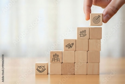 Business Strategy Planning. Hand stacking wooden cubes into step structure with partnership growth and goal symbols, symbolizing scalable development strategic alignment and performance improvement.
