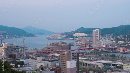 Nagasaki, Japan. Aerial timelapse made from a hill in Nagasaki, Japan, with a view over the entire center, including the bay and the hills. Cloudy and sunny morning in summer, zoom in