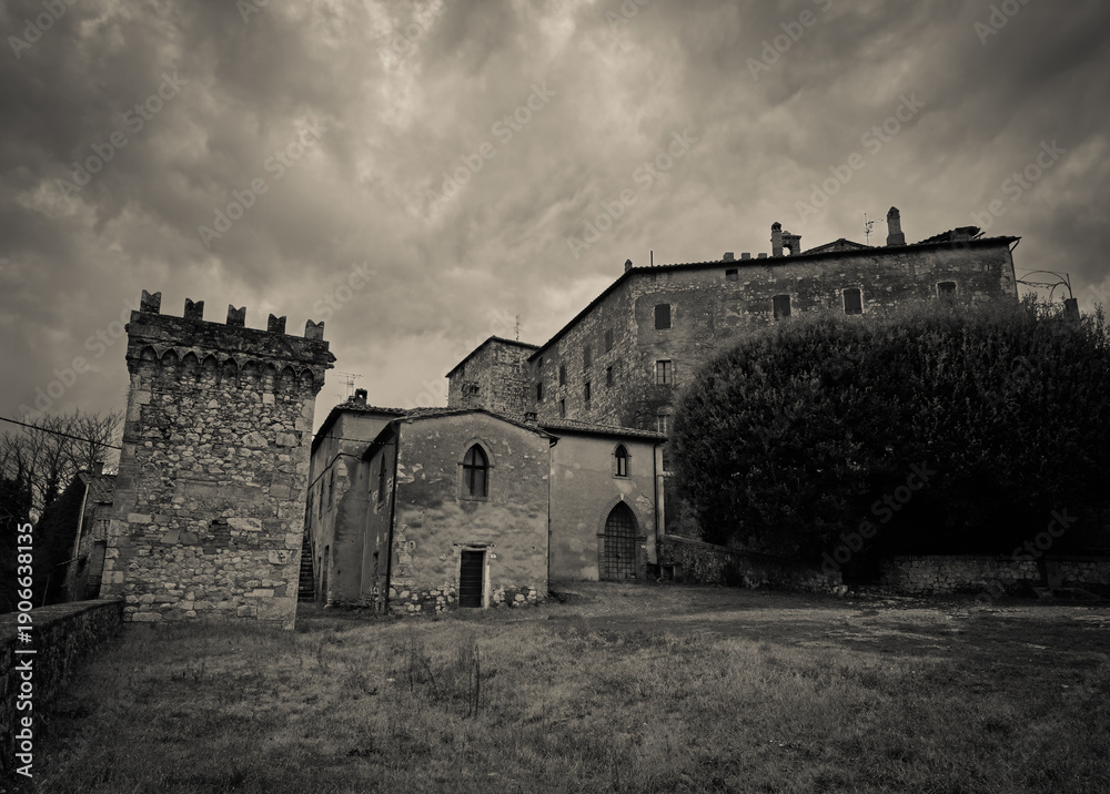 Fototapeta premium VIew of Frosini medieval Tuscan village features an ancient stone watchtower with Guelph battlements and historical fortified buildings nestled among green hills