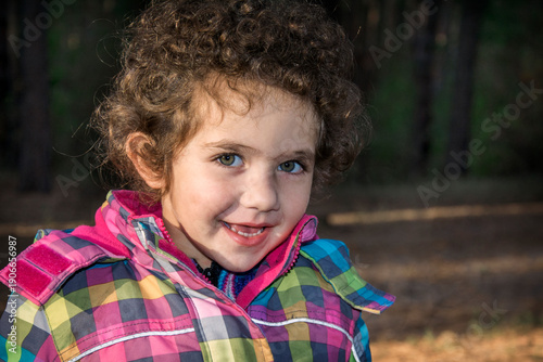 Autumn in the woods a little curly girl laughing.