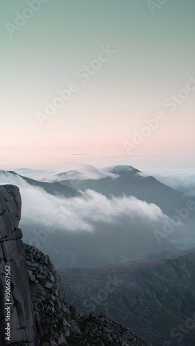A serene mountain range above the clouds during a peaceful sunrise creates an ethereal atmosphere