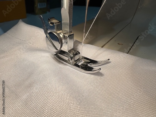Billede på lærred Sewing machine needle and presser foot on white fabric, conceptual close up for textile craft, fashion design, and handmade hobby