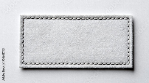 Close-up of a blank white label with stitched edges on a white background.