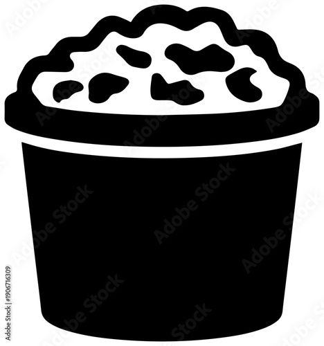 Black filled icon of a round tub of ice cream with chunks on top isolated on white background