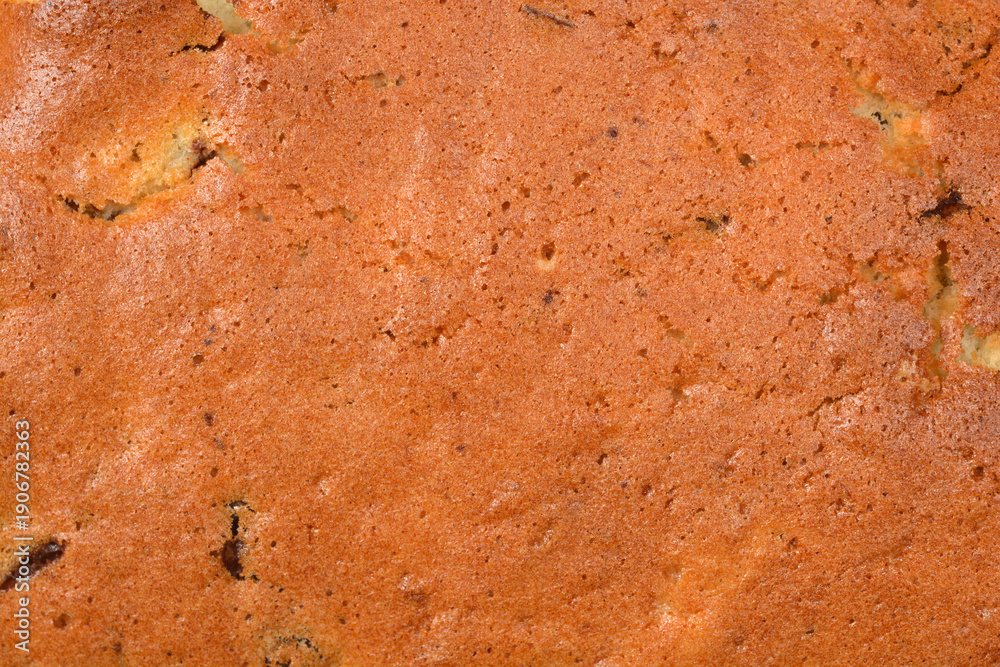 © nahhan - A high resolution macro shot of a golden brown baked sponge cake surface showing porous texture and small crumbs
