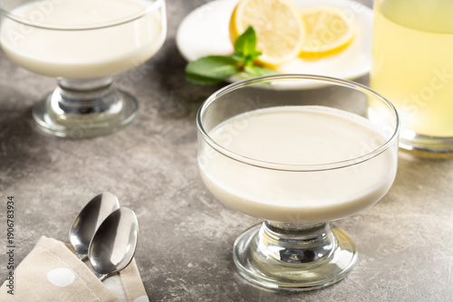 Classic lemon posset dessert with limoncello served in glass bowl on stone table, elegant plated dessert photography.