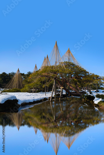 Canvas Print Tranquil Gyokusen‑inmaru Garden landscape with water reflections and yukitsuri, or snow hanging using a central bamboo pole with ropes attached to branches, in Kanazawa, Ishikawa, Japan