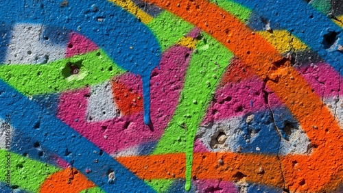 Vibrant graffiti adorns a weathered concrete wall with abstract shapes and colors from a close-up view