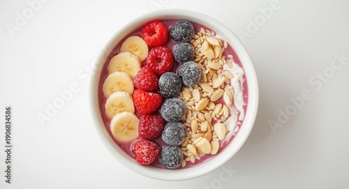 Healthy fruit smoothie bowl with yogurt banana and berries topped with frozen blackcurrant almonds and sesame seeds with a white bowl top view and copy space