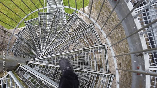 A person descends an iron spiral staircase