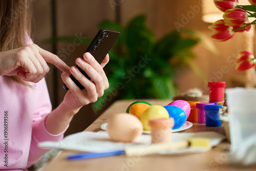 Wallpaper Mural Woman photographing painted Easter eggs and craft supplies on table with smartphone. Concept of sharing holiday moments, social media and digital lifestyle. Torontodigital.ca