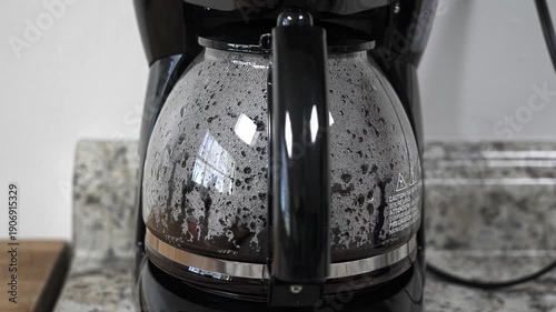 Freshly brewed coffee filling a glass pot in an automatic drip coffee machine. A hot beverage preparing in a modern kitchen appliance