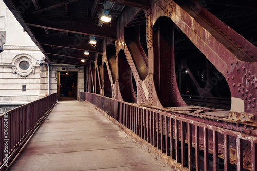 Old iron bridge walkway with riveted beams and city building in background. Chicago, Illinois, USA