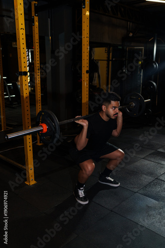 Strong Athletic Man Performing Barbell Back Squat in Modern Gym