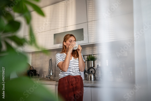 Obraz na płótnie Woman drinking morning coffee in modern kitchen sunlight