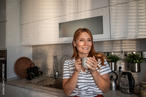 Tableau sur toile Woman smiling relaxing enjoying morning coffee in kitchen