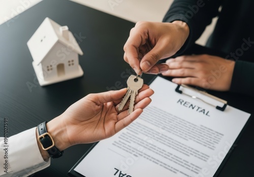 Hands exchanging keys for rental property with contract on table