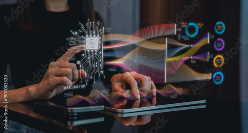 A person interacts with a futuristic touchscreen interface displaying colorful data visualizations and circuit patterns.