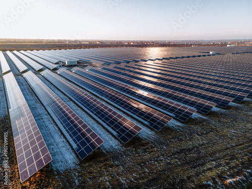 Large Scale Solar Power Plant with Rows of Photovoltaic Panels in Open Field During Cold Season Captured from Aerial Drone Perspective