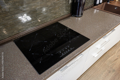 Tableau sur toile Modern kitchen with black induction cooktop, speckled granite countertop, white