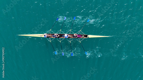 Aerial drone top down photo of team of Athletes rowing in sport canoe in emerald deep blue sea
