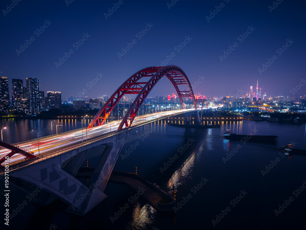 Obraz premium Night aerial view of Guangzhou with illuminated bridge and city skyline, concept highway car jam of China