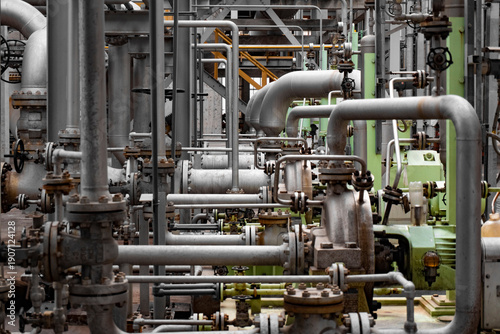 Complex network of industrial pipelines, valves, and machinery inside a chemical plant. Interconnected metal pipes and processing equipment illustrate engineering precision, industrial operations, and