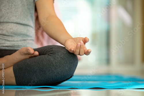 Wallpaper Mural Person practicing meditation in lotus pose on yoga mat indoors, focusing on mindfulness and relaxation, representing mental health, wellness lifestyle, stress relief, and balanced living Torontodigital.ca