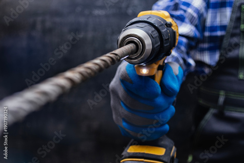 Photos Close up of construction worker using electric power drill with masonry bit to drill concrete wall