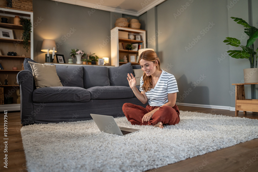 Obraz premium Young woman having video call waving hand on laptop