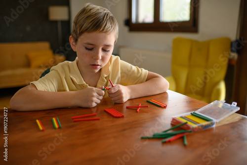 Wallpaper Mural Boy sitting at a table at home using wooden counting sticks to learn math. Child practicing basic arithmetic and number skills in a calm home learning environment. Torontodigital.ca