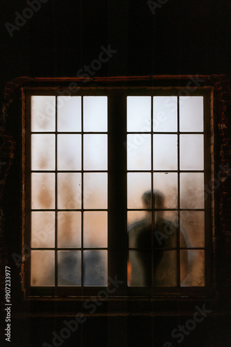 Silhouette of person behind a frosted window at night